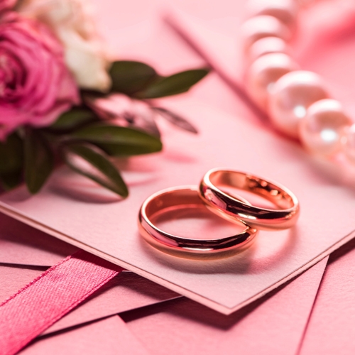 two wedding rings on top of wedding invitations